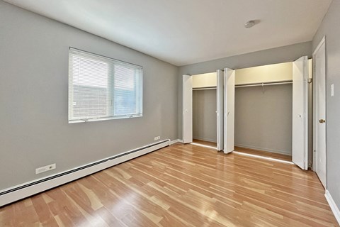A room with wooden flooring and a window with blinds.