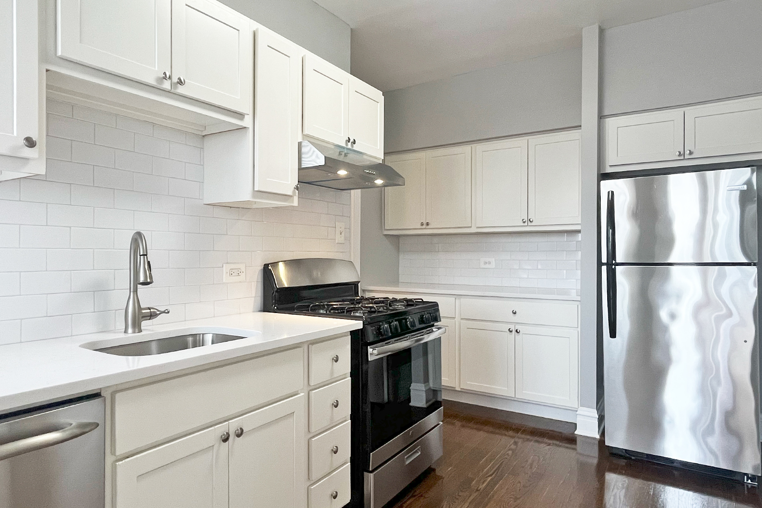 A kitchen with white cabinets and a stainless steel refrigerator.
