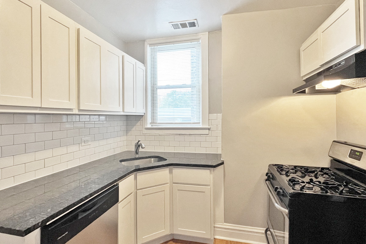 a kitchen with white cabinets and a stove and a sink