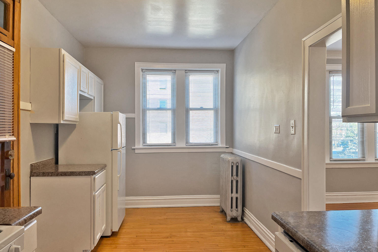 A kitchen with white cabinets and a window.