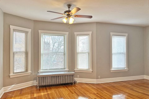 A room with a ceiling fan and three windows.