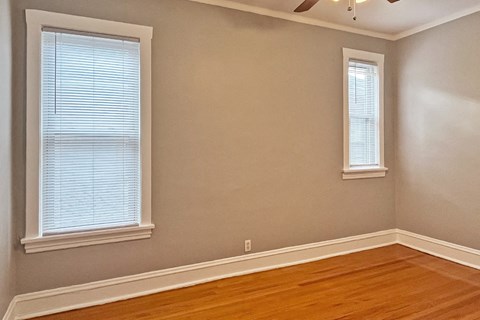 A room with wooden floors and two windows.