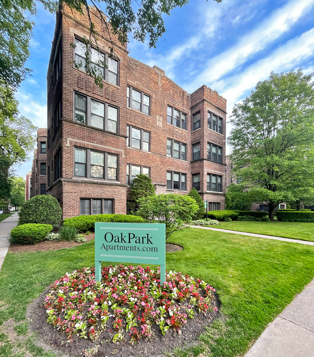 A sign for Oak Park Apartments is in front of a brick building.