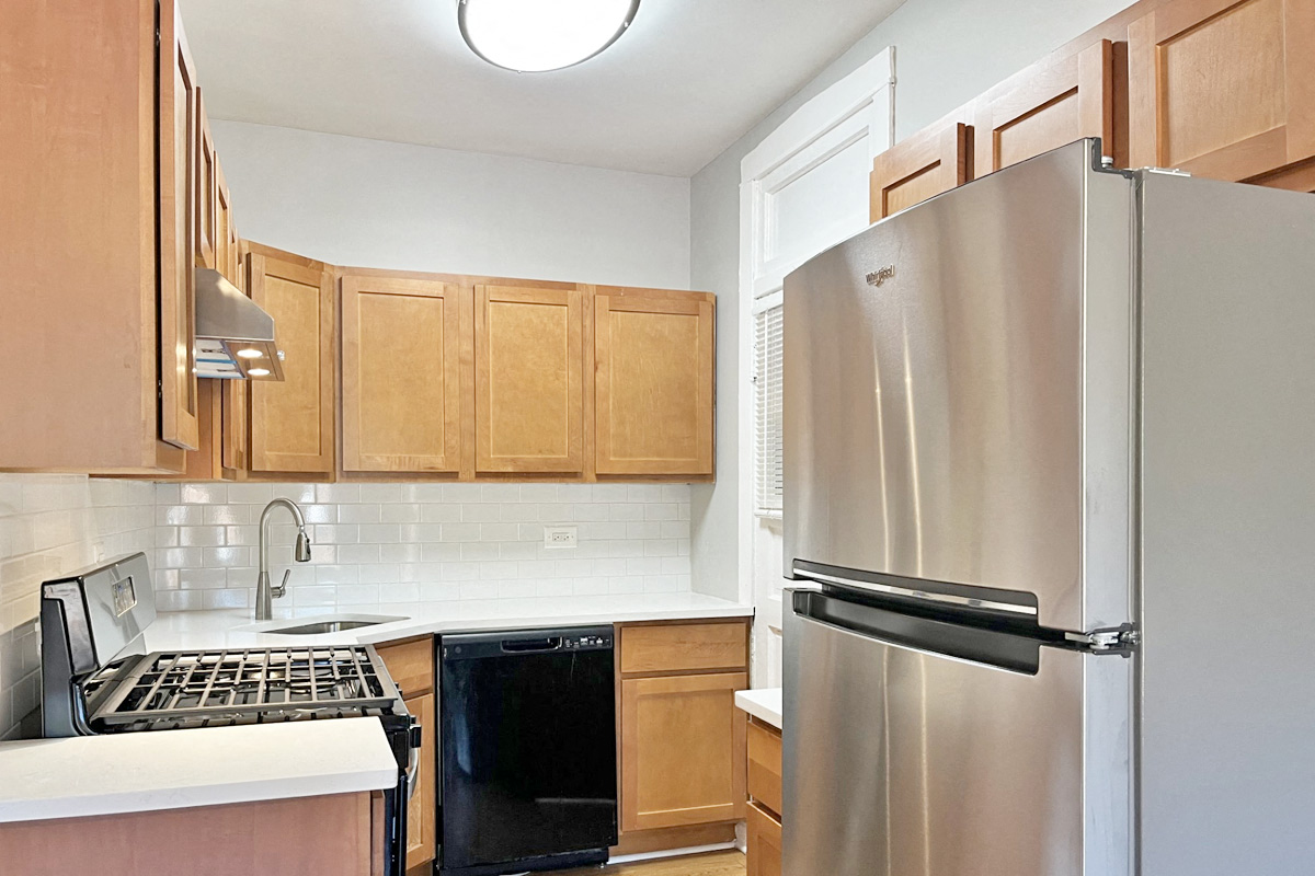 A kitchen with a stainless steel refrigerator and wooden cabinets.