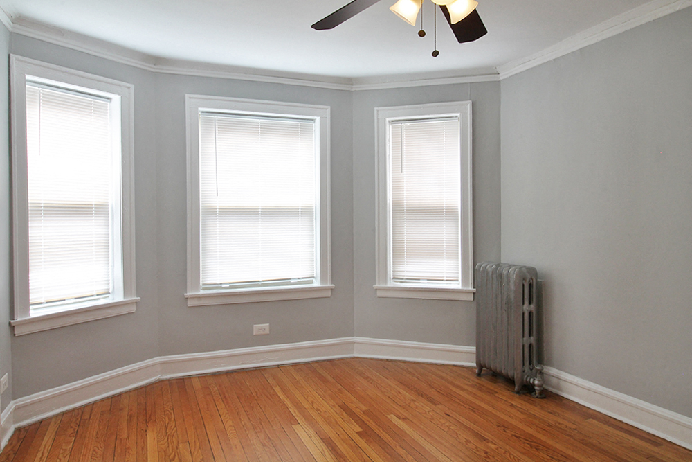 three windows in a room with wood floors and a radiator