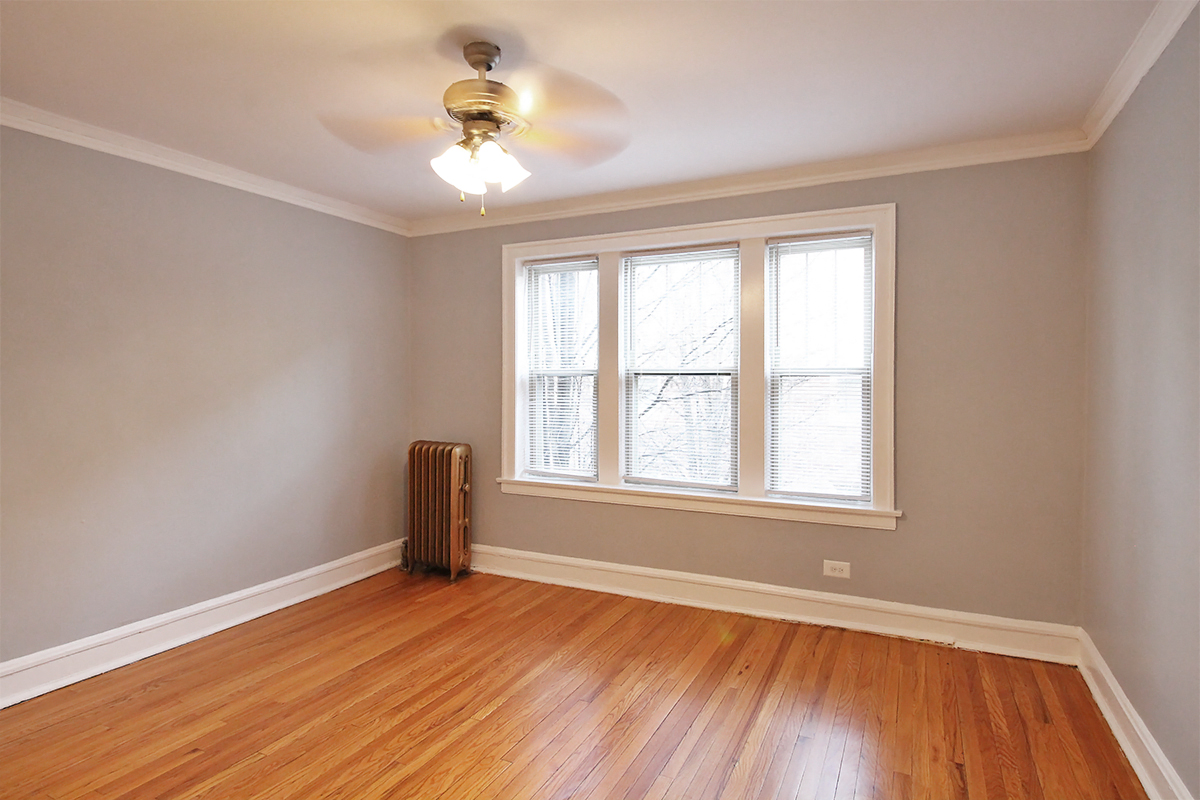 an empty living room with wood floors and a ceiling fan