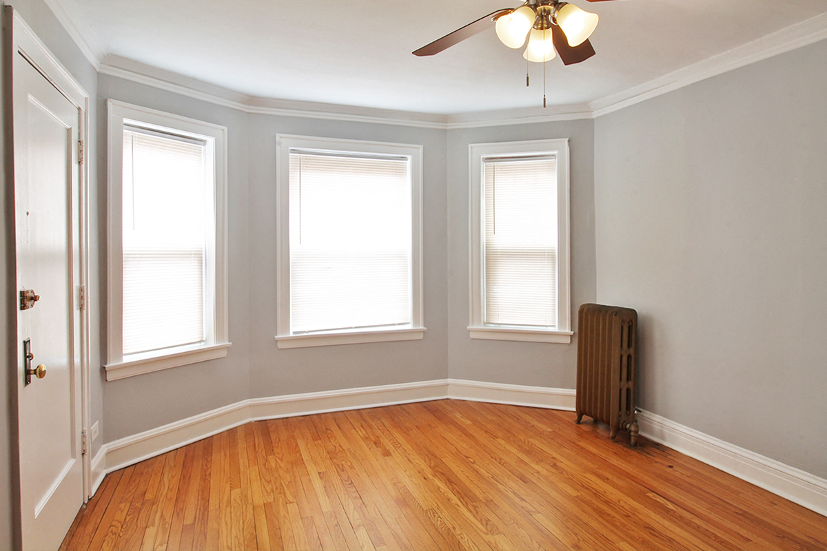 an empty room with a radiator and three windows