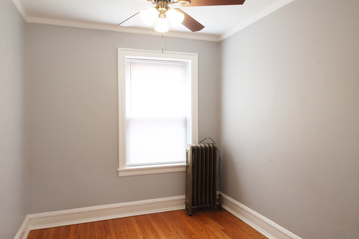 an empty room with a radiator and a ceiling fan