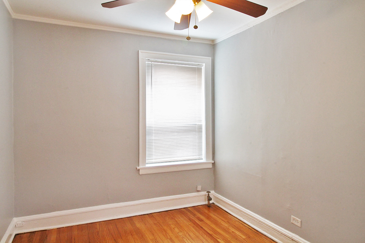 an empty room with a window and a ceiling fan