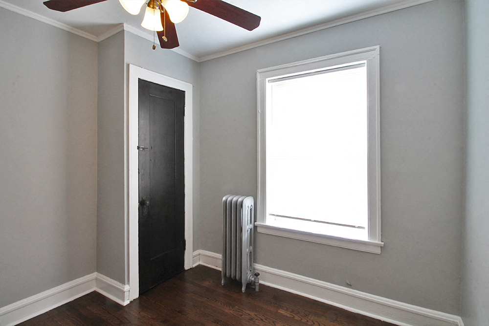 a room with a radiator and a window and a ceiling fan