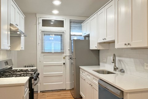 A kitchen with white cabinets and a black stove top.