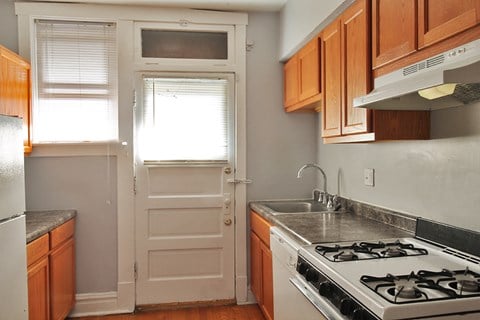 a kitchen with a stove and a white door with a window
