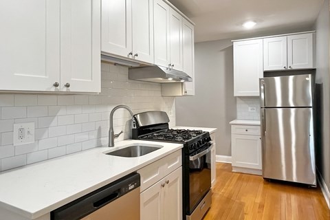 A kitchen with white cabinets and a stainless steel refrigerator.