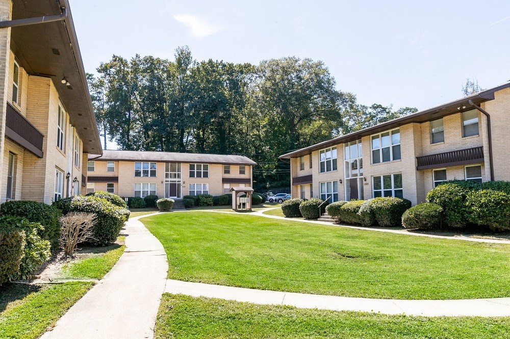 the outlook of an apartment building with a lawn and sidewalk