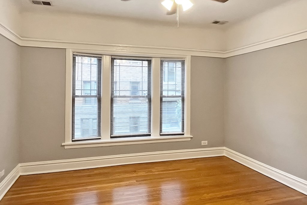 A room with wooden floors and two windows.