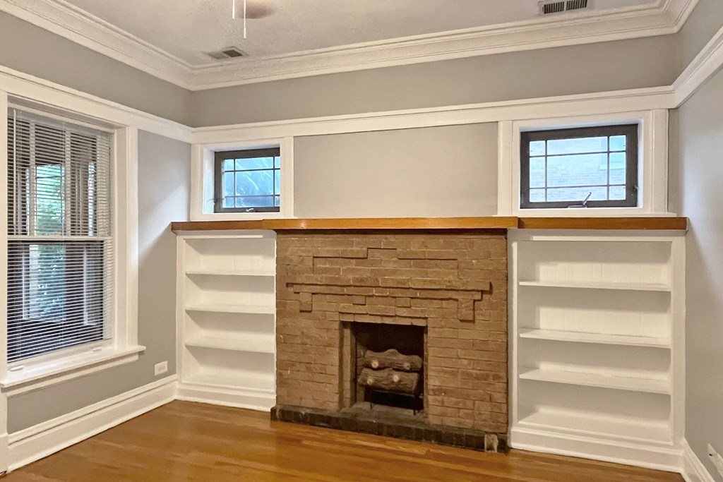 A fireplace with a white mantle and a window above it.