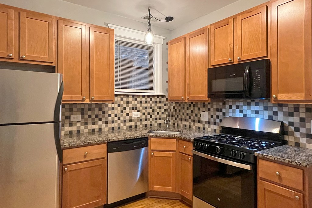 A kitchen with wooden cabinets and a black and white checkered backsplash.