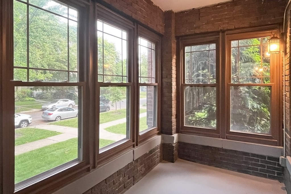 A room with a brick wall and a large window overlooking a street.