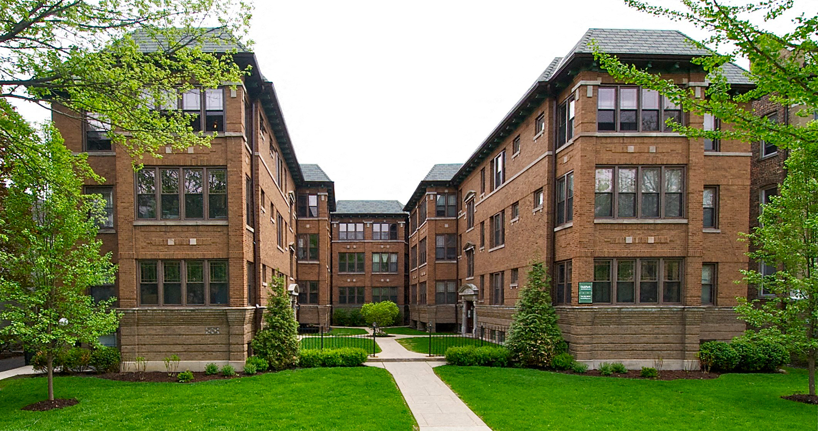 a row of brick apartment buildings with green grass and trees