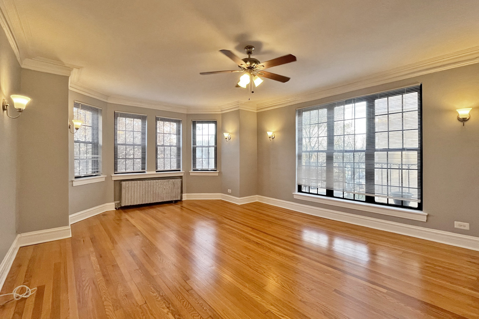 A room with a ceiling fan and wooden floors.