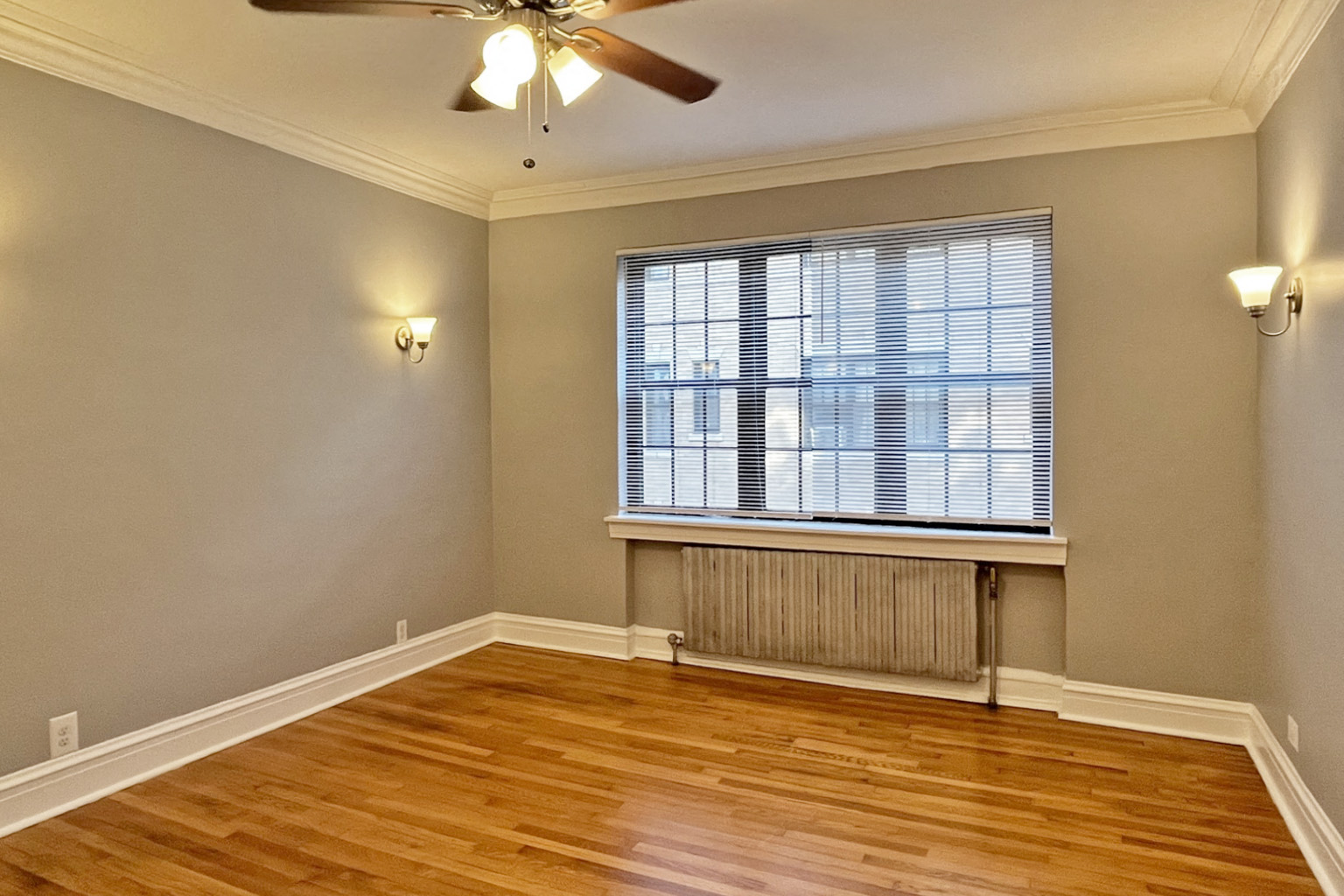 A room with a ceiling fan and a window with blinds.