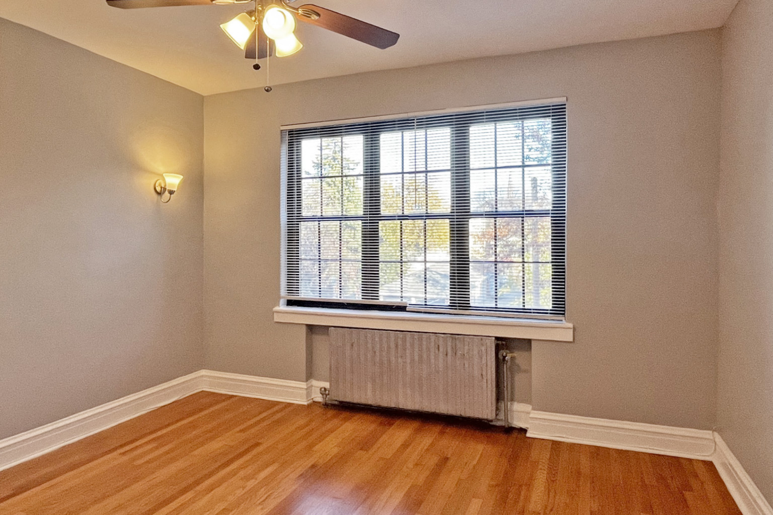 A room with a window and a fan on the ceiling.