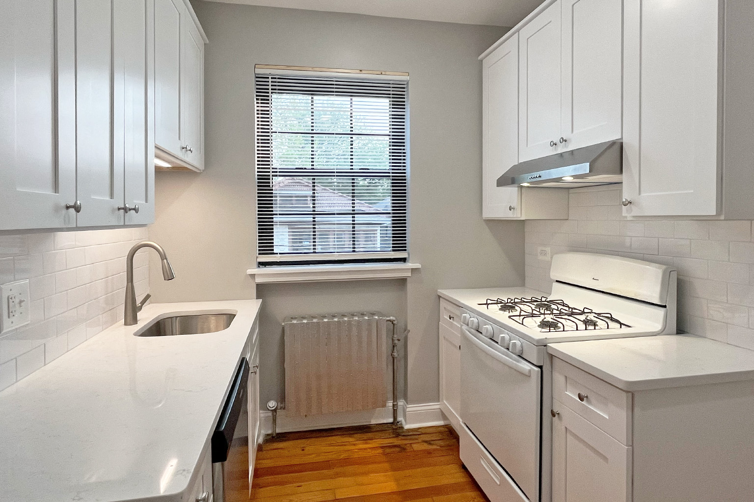 A kitchen with white cabinets and a stove top oven.