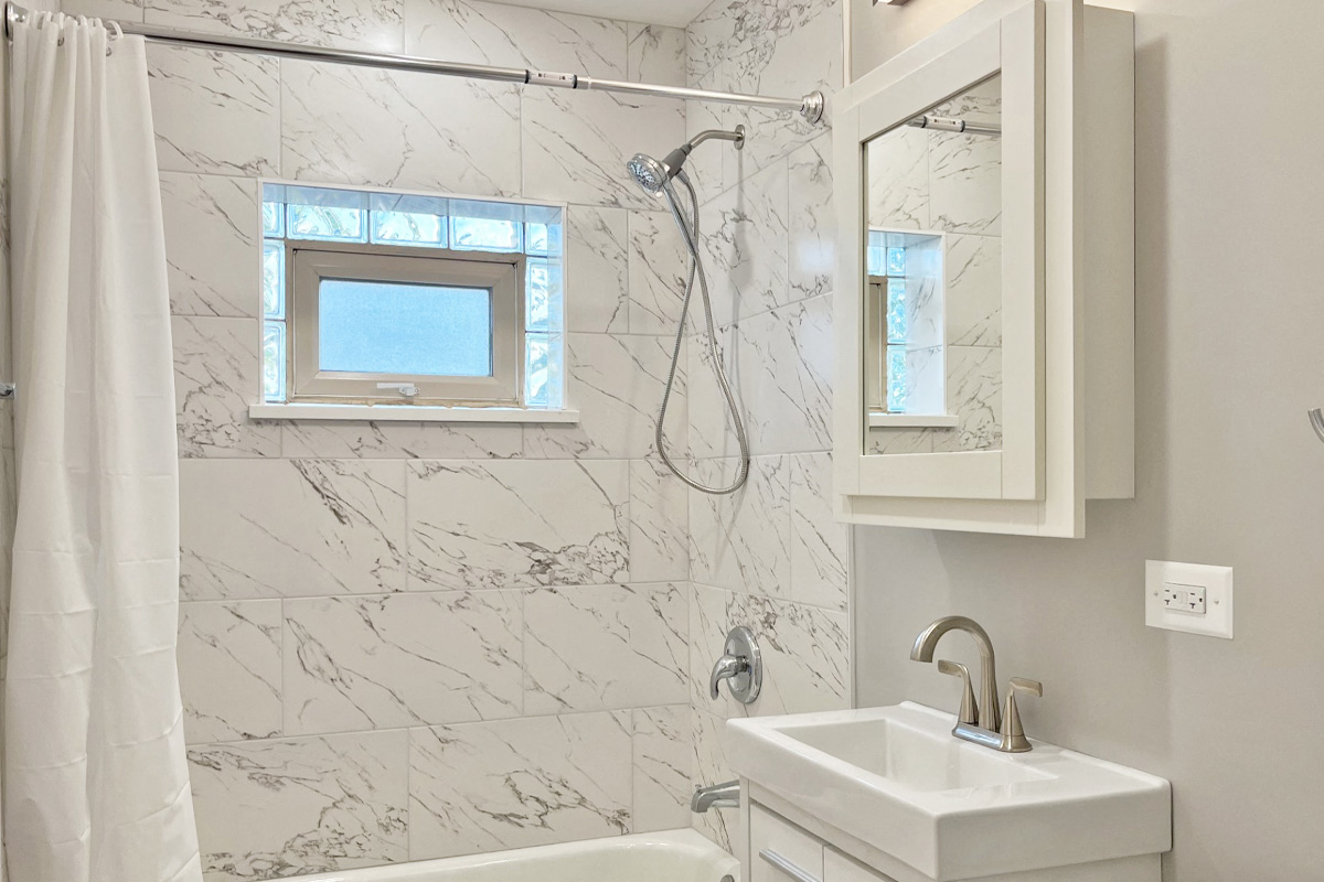 a bathroom with a shower and a sink and a window