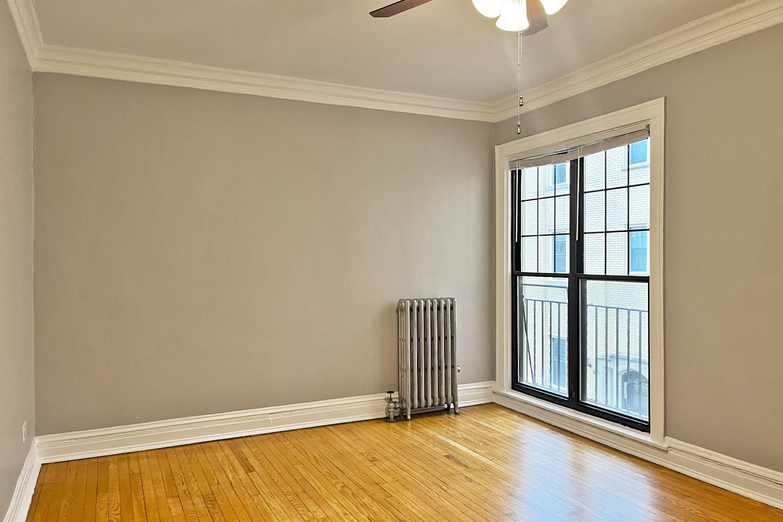 A room with a window and a radiator on the floor.