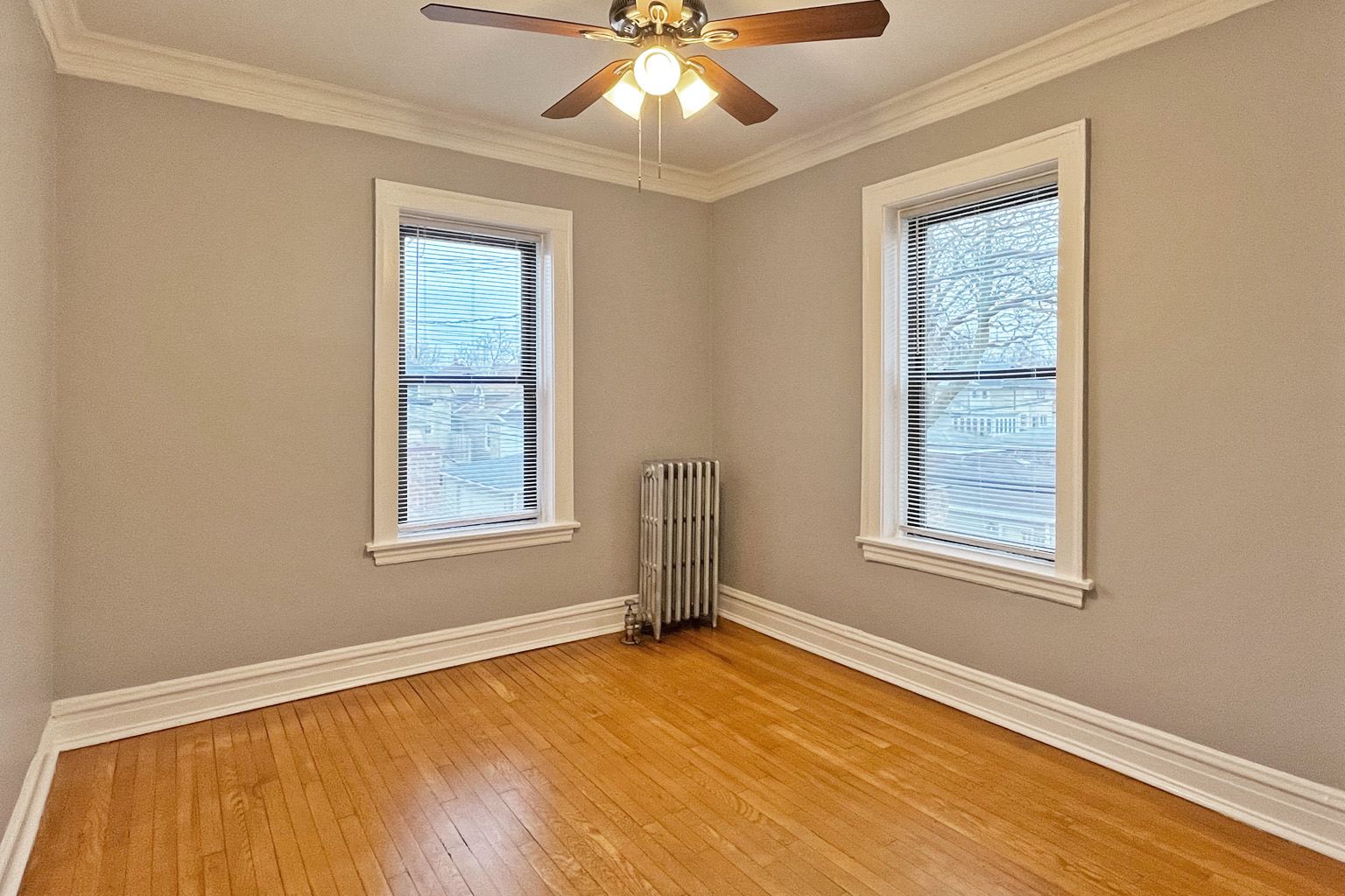 A room with a ceiling fan and two windows.