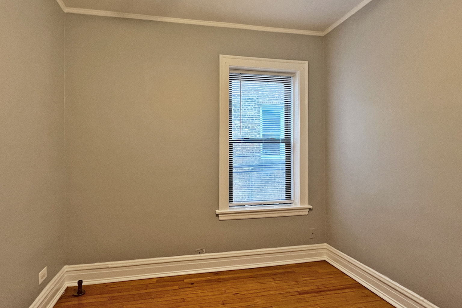 A room with a window and wooden floors.