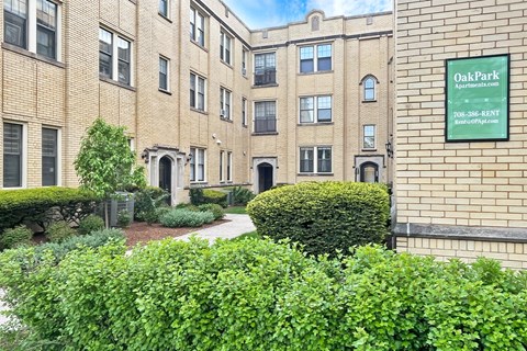 A building with a green hedge in front of it and a sign that says Oak Park.