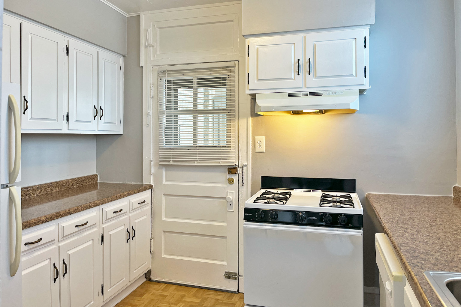 A kitchen with white cabinets and a black stove top.