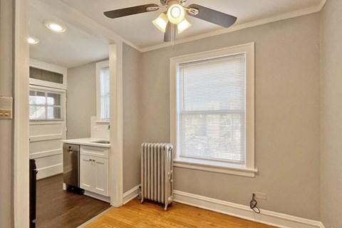 A room with a ceiling fan and a window with blinds.