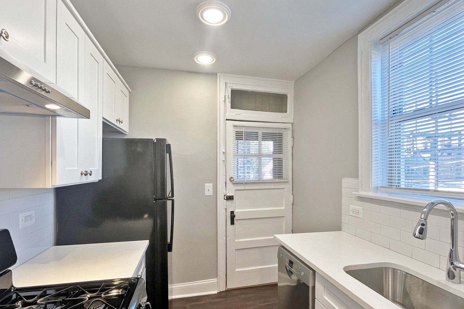 A kitchen with white cabinets and a black fridge.