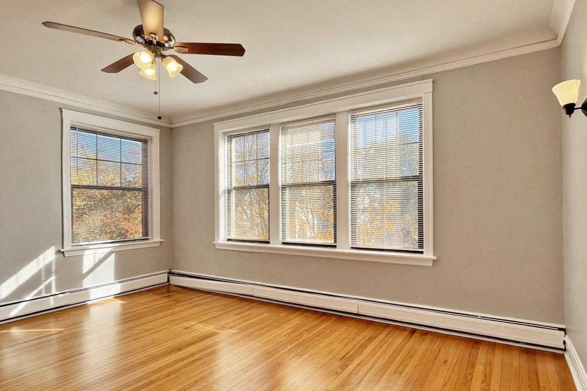 an empty living room with a ceiling fan and windows