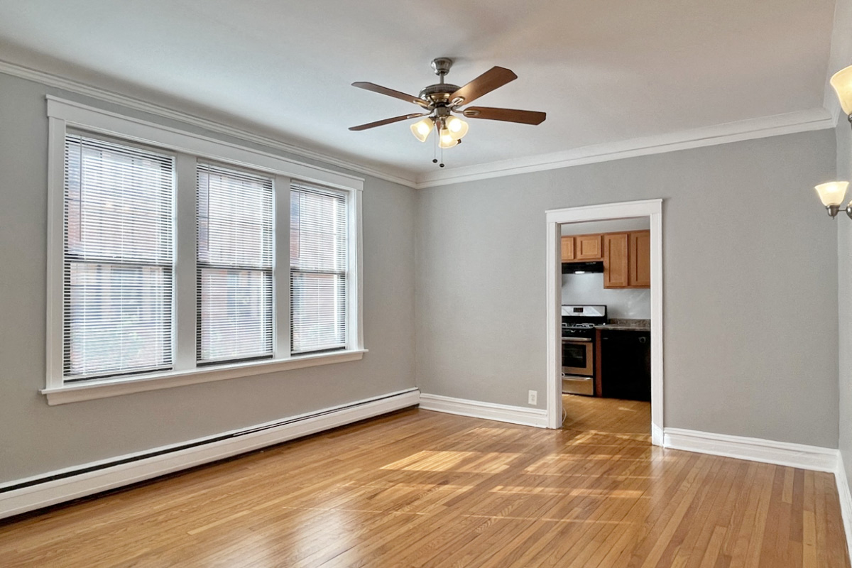 an empty living room with a ceiling fan and windows