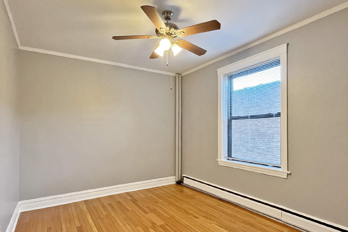 an empty room with a ceiling fan and a window