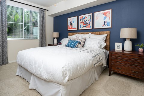 A bedroom with a white bed and a wooden nightstand.