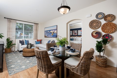 A dining room with a table set for four and a couch with a pillow.