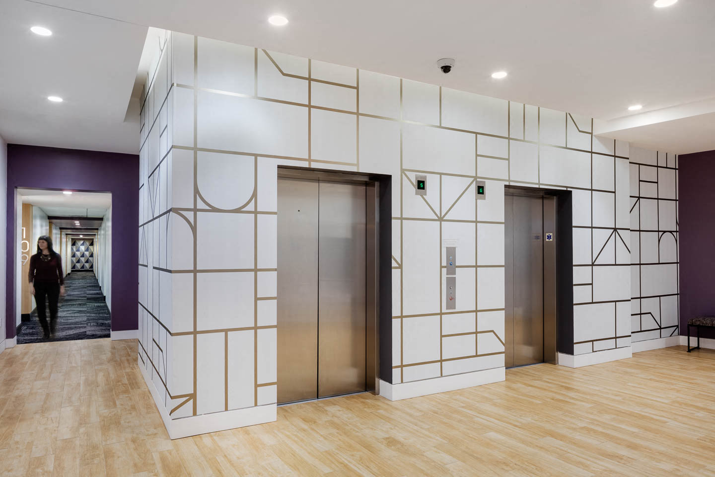 a lobby with two elevators and a wood floor and white walls