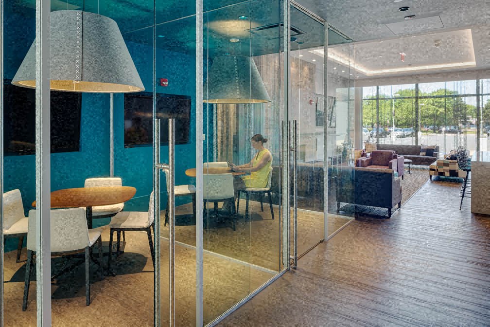 a man sitting at a table in a room with glass walls
