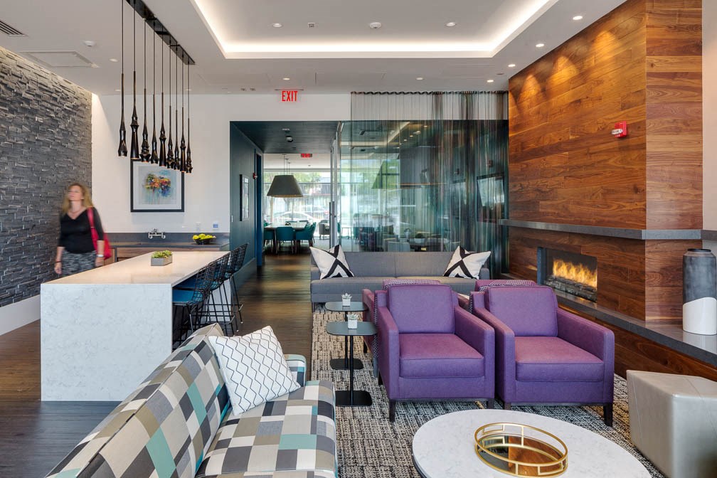 a hotel lobby with purple chairs and a fireplace