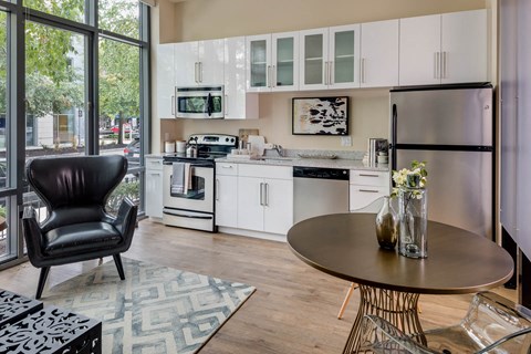 a kitchen with white cabinets and a table in a living room