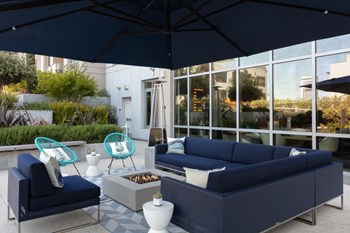 Pet-Friendly Apartments in San Francisco CA - Etta - Outdoor Lounge Area Features a Large Couch and Extra Chairs Surrounding a Fireplace. - Photo Gallery 24