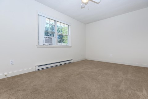 an empty living room with a window and carpet