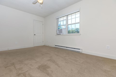 an empty living room with a window and carpet