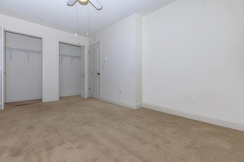an empty living room with white walls and a door to a closet