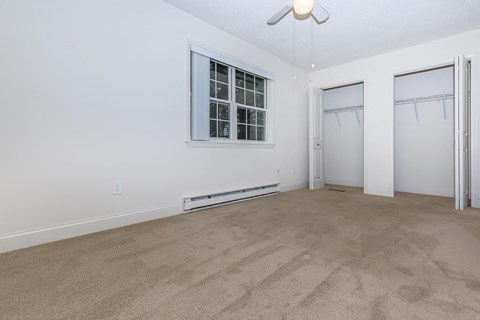 a living room with carpet and white walls and a window