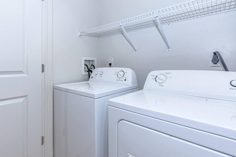 a white laundry room with two washes and a dryer